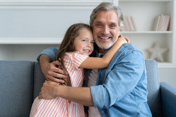 Obraz premium Happy sweet girl hugging her father at home