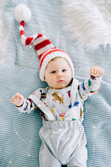 the child's first Christmas. a cute little boy in a Santa hat. lying on the bed. view from the top.Christmas concept