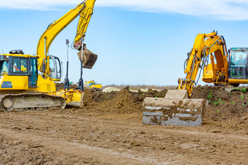 Obraz premium Two excavators and earthmover are leveling ground construction site