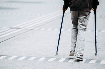 Homme qui marche dans la rue avec des béquilles
