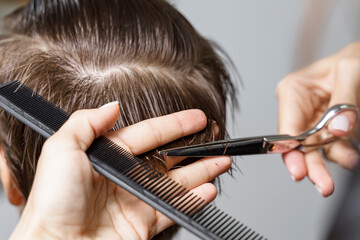 hair cutting process close up. scissors and comb in the hands of a professional hairdresser