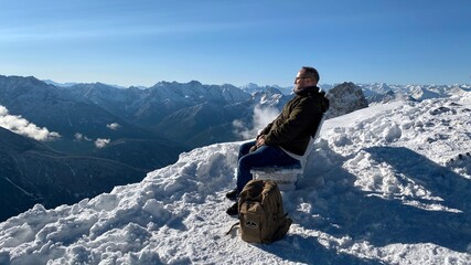 Man sitting on bench on snowy mountain top - 386351144