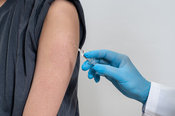 The doctor is injecting male patients. In the medical's hand have syringes.