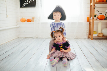 Boy in a pirate costume and a girl in a witch costume celebrates Halloween at home