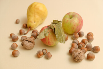 Apple, pear and nuts on a cream background closeup