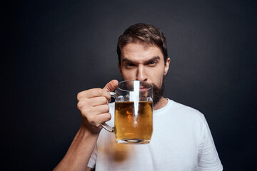 man with a mug of beer in a white t-shirt emotions lifestyle drunk on a dark isolated background