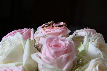 pink themed wedding bouquet with two wedding rings on top 