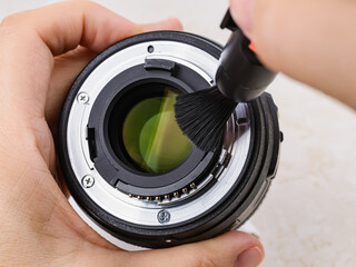 Hands sweeping a dust from a rear camera lens using a lens pen brush. Routine removal of dust and...