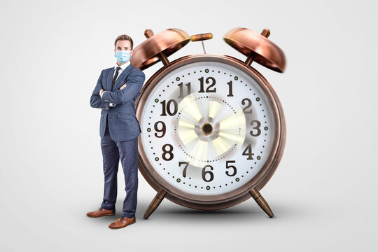 Businessman With A Mask Standing Next To A Clock With Spinning Hands