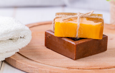 Two bars of soap and a towel on a wooden platter.
