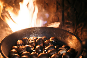 Roasting chestnuts with fire and wood in a fireplace at home. Celebrating the 