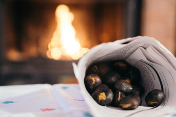 Chestnuts inside a cone with the fireplace in the background. Making roasted chestnuts at home. Celebrating 