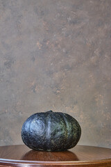 black coloured pumpkin with glitter on wooden stool in front of a brown backdrop