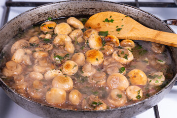 Cooking vegan mushroom fricassee with garlic and onions in a frying pan - garlic mushrooms, French cuisine.