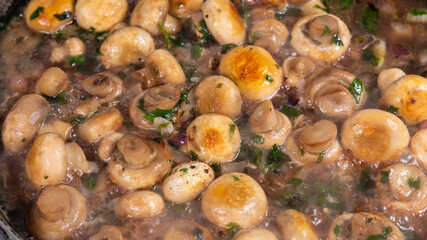 Cooking vegan mushroom fricassee with garlic and onions in a frying pan - garlic mushrooms, French cuisine.
