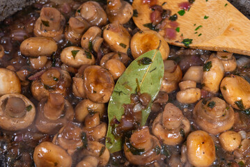 Cooking vegan mushroom fricassee with garlic and onions in a frying pan - garlic mushrooms, French cuisine.