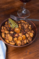 Vegan mushroom fricassee with garlic in a clay plate on a rustic wood background top view - mushrooms with garlic