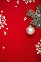 Fototapeta na wymiar Christmas background with fir tree twig, white Christmas ball and snowflakes on red copy space.