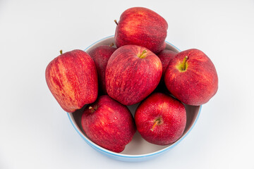 Pile of red apple in blue bowl with clear water drop on 
shell surface texture pattern isolated, white background