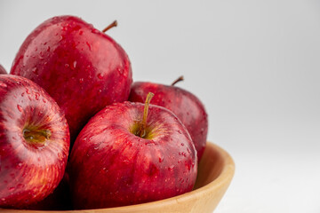 Pile of red apple in wooden bowl with clear water drop on 
shell surface texture pattern isolated, white background