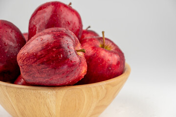 Pile of red apple in wooden bowl with clear water drop on 
shell surface texture pattern isolated, white background