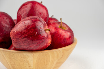 Pile of red apple in wooden bowl with clear water drop on 
shell surface texture pattern isolated, white background