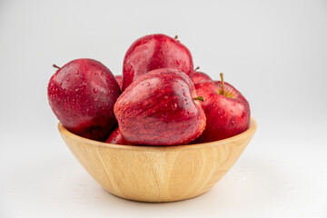 Pile of red apple in wooden bowl with clear water drop on 
shell surface texture pattern isolated, white background