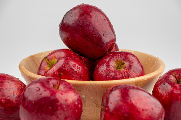Pile of red apple in wooden bowl with clear water drop on 
shell surface texture pattern isolated, white background