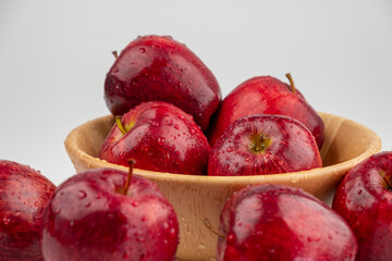 Pile of red apple in wooden bowl with clear water drop on 
shell surface texture pattern isolated, white background