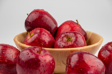 Pile of red apple in wooden bowl with clear water drop on 
shell surface texture pattern isolated, white background