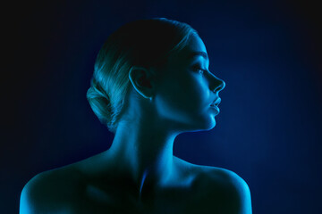Passion. Portrait of female fashion model in neon light on dark studio background. Beautiful...