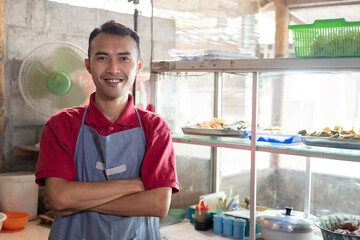 close up of the food stall seller smiling with crossed hands while looking at the camera against...