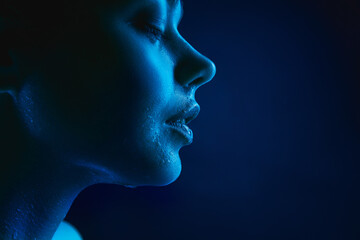Obraz premium Night. Portrait of female fashion model in neon light on dark studio background. Beautiful caucasian woman with trendy make-up and well-kept skin. Vivid style, beauty concept. Close up. Copyspace