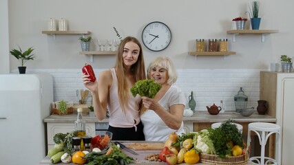 Mature woman with grandchild girl recommending eating raw vegetable food. World vegan day concept
