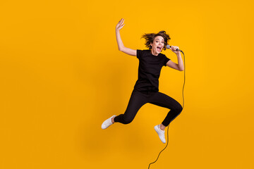 Fototapeta na wymiar Full length body size view of pretty cheerful funky skinny girl artist jumping singing rock isolated bright yellow color background