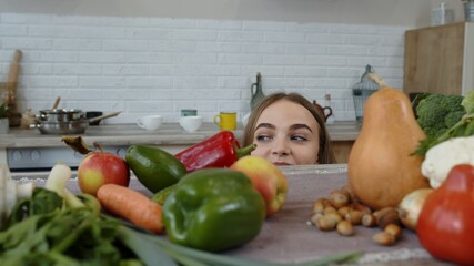 Girl peeping from under the table for vegetable and fruits. Weight loss, diet concept