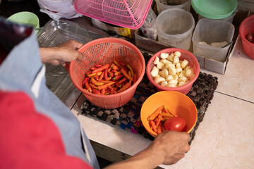Close up of waiter's hands preparing seasoning in basket and bowl for basic cooking spices
