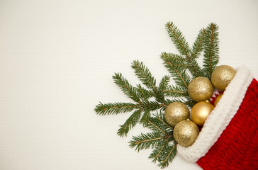 Christmas composition of balls and fir branches in a Santa Claus hat on a white wooden background