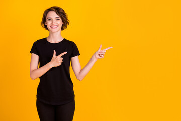 Portrait of nice lovely confident cheerful girl pointing two forefingers copy empty space isolated over bright yellow color background