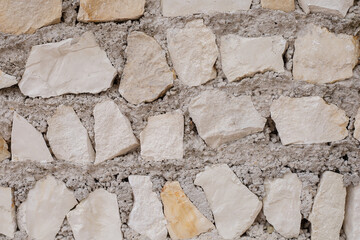 background of ancient stone wall of beige color close up