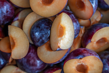 Food background of cutted halfs of blue plums. Top view with selective focus