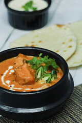 Butter chicken bowl and naan bread on wooden table. Curry - Meal, Indian food.