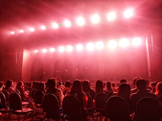 Blurred crowd at social distancing concert venue in Thailand during the coronavirus (covid-19) : Silhouette happy people sitting in front of stage with bright laser light beam.The New Normal