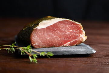 Gerky pork with spices, fresh green thyme, slate cutting board on wooden table. Polendwitz