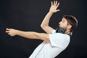 Man with joystick in hands headphones technology leisure game lifestyle dark isolated background