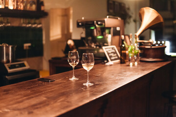 Two glasses of white wine in a dark cozy bar. Wine served on a wooden table