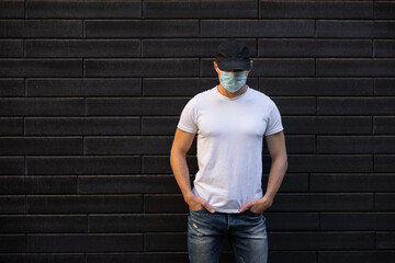 Man in white t-shirt standing against brick wall, mockup design