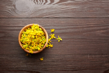 Hypericum perforatum fresh flowers buds in wooden bowl on dark table, top view