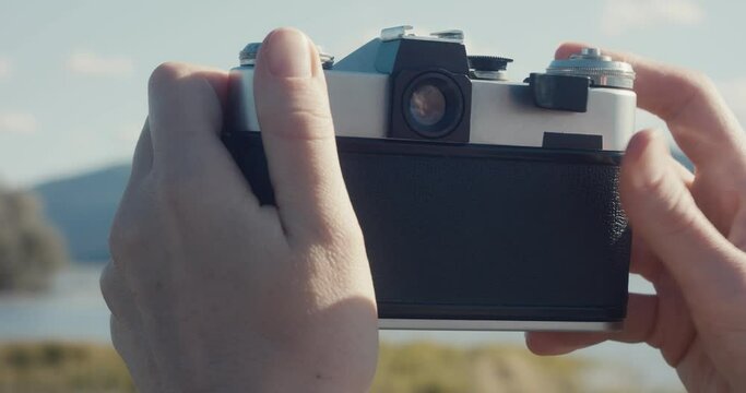 Blonde woman take photo with analog camera at lake outdoors close up