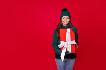 Portrait of her she nice attractive lovely cute dreamy cheerful girl holding in hands giftbox thinking fantasizing copy space isolated over bright vivid shine vibrant red color background